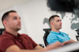 grupo de homem de negócios casual trabalhando no computador desktop no interior do escritório de inicialização de plano aberto moderno. foco seletivo foto