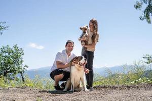 jovem casal viajando com cães nas montanhas, cachorro st.bernard e yourkshire terrier foto