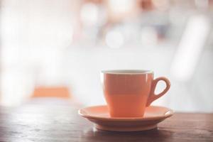 xícara de café laranja na mesa de madeira foto