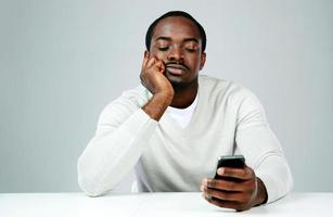 homem africano pensativo usando smartphone