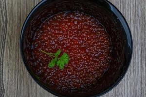 caviar vermelho em uma tigela sobre fundo de madeira foto