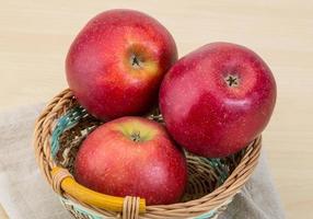 maçãs vermelhas em uma cesta em fundo de madeira foto
