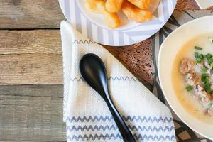 mingau de estilo chinês ou mingau e vara de massa frita ou vara de massa frita ou rosquinha ou pão frito colocado em uma mesa de madeira. comida de rua tailandesa é chamada de mingau e patongo. foto