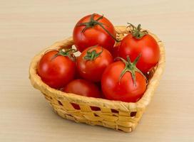 tomate cereja em uma cesta em fundo de madeira foto