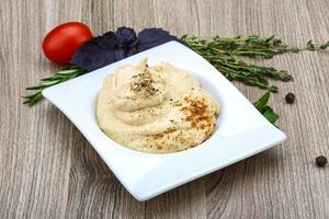 hummus em uma tigela com fundo de madeira foto