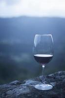 copo de cristal de vinho tinto na parede de pedra com o céu foto