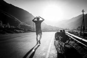 ciclista ciclista viajando frustrado com as mãos na cabeça nas montanhas enquanto faz passeios de bicicleta. estresse e medos durante a viagem. imagem em preto e branco. foto