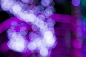 efeitos de luz bokeh abstratos de desfocagem rosa roxo na textura de fundo preto da noite foto