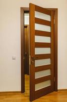 buraco da fechadura e puxador de metal de uma porta de madeira. porta de madeira marrom com vidro foto