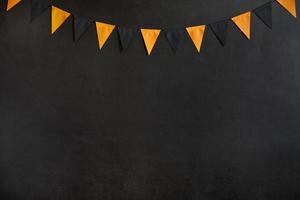 guirlanda de halloween de bandeiras pretas e laranja em um fundo escuro com espaço para texto foto