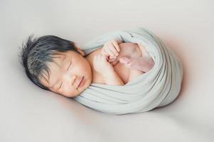 bebê recém-nascido asiático embrulhado em casulo dormindo foto