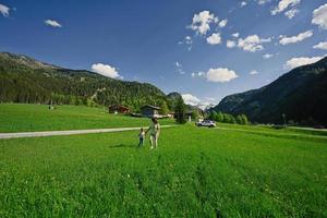 mãe de mãos dadas filha e andando no prado alpino em untertauern, áustria. foto