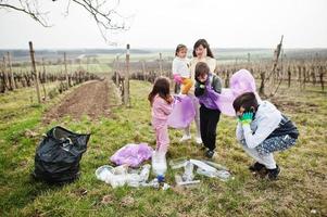 família com saco de lixo coletando lixo durante a limpeza nas vinhas. conservação ambiental e ecologia, reciclagem. foto