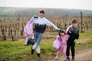 crianças com saco de lixo coletando lixo durante a limpeza nas vinhas. conservação ambiental e ecologia, reciclagem. foto