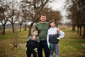 pai com dois filhos trabalhando no jardim primavera. foto