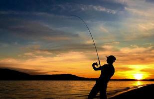 jovem pescando ao pôr do sol foto