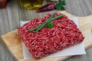 carne picada na tábua de madeira e fundo de madeira foto