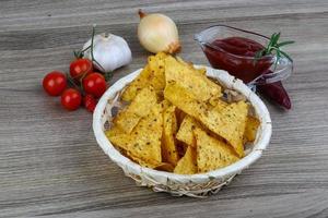 nachos em uma cesta em fundo de madeira foto