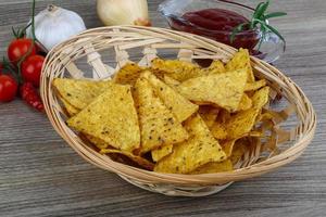 nachos em uma cesta em fundo de madeira foto