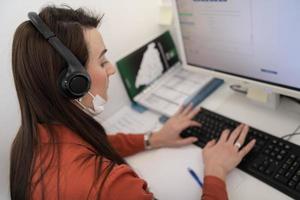 operador de call center com máscara médica foto