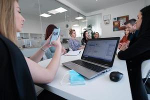 mulher de negócios como líder de equipe na reunião verificando mensagens telefônicas foto