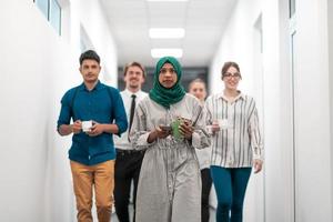 equipe de negócios de inicialização multiétnica andando pelo corredor do prédio enquanto voltava de uma pausa para o café foto