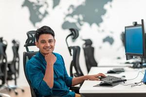 homem de negócios casual trabalhando no computador desktop no interior do escritório de inicialização de plano aberto moderno. foco seletivo foto