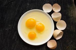 três ovos crus quebrados em um prato branco