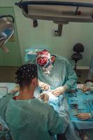 cirurgião e seu assistente realizando cirurgia plástica no nariz foto