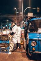 velho cozinhando salsichas na rua foto