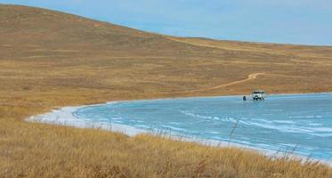 jipe militar russo para viagem de inverno e um turista na superfície de gelo do lago baikal. foto
