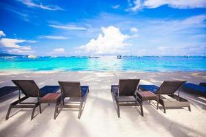 cadeiras na exótica praia tropical de areia branca foto