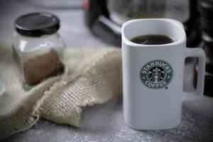 Washington - EUA setembro, 26 2022 caneca de café starbucks na mesa cinza com garrafa de café e moedor de café. foto