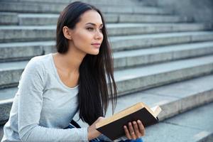 mulher sentada na escada da cidade com livro ao ar livre