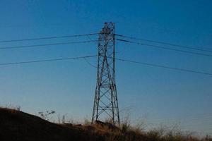 torres elétricas de silhueta suportando cabos de cobre para transportar energia elétrica foto