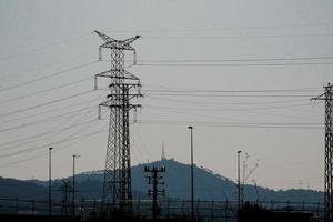 torres elétricas de silhueta suportando cabos de cobre para transportar energia elétrica foto