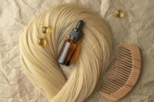um óleo essencial de tratamento capilar para alisar o cabelo deitado em um fio de cabelo loiro foto