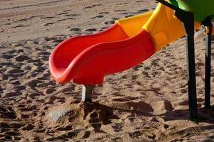 escorregador colorido na areia da praia, jogos infantis foto