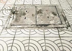 a tampa de bueiro de concreto no pavimento da via de tijolos. foto
