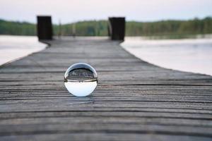 bola de vidro em uma passarela de madeira em um lago sueco na hora azul. natureza escandinavia foto