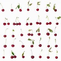 muitas cerejas vermelhas maduras dispostas em branco foto