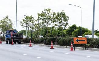 sinal de trânsito laranja com ícone de seta e cones de sinal na estrada foto