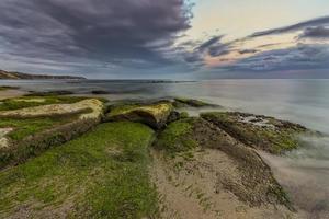 tarde verde. Seascape de praia rochosa ao pôr do sol. foto