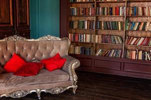 interior clássico de luxo da biblioteca em casa. sala de estar com estante, livros, poltrona, sofá e lareira. decoração clean e moderna com móveis elegantes. educação leia o conceito de sabedoria de estudo. foto