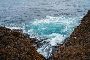 onda do mar sobre rochas e algas foto