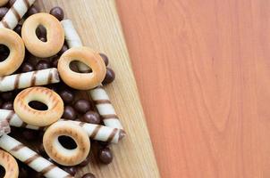 túbulos crocantes, bolas de chocolate derretendo e bagels estão em uma superfície de madeira. mistura de vários doces foto