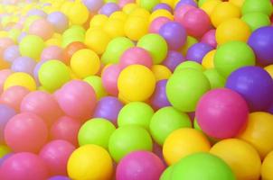 muitas bolas de plástico coloridas em uma piscina infantil em um playground. padrão de close-up foto