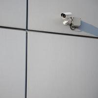 câmera de vigilância branca embutida na parede de metal do prédio de escritórios foto