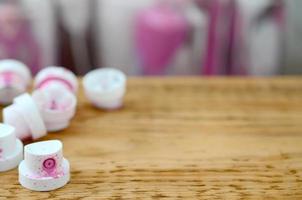 os bicos cor-de-rosa sujos do pulverizador de tinta encontram-se numa prancha de madeira sobre um fundo de muitas latas de spray sujas foto