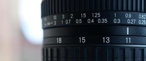 fragmento de uma lente zoom grande angular para uma câmera slr moderna. o conjunto de valores de distância é indicado por números brancos no corpo preto foto